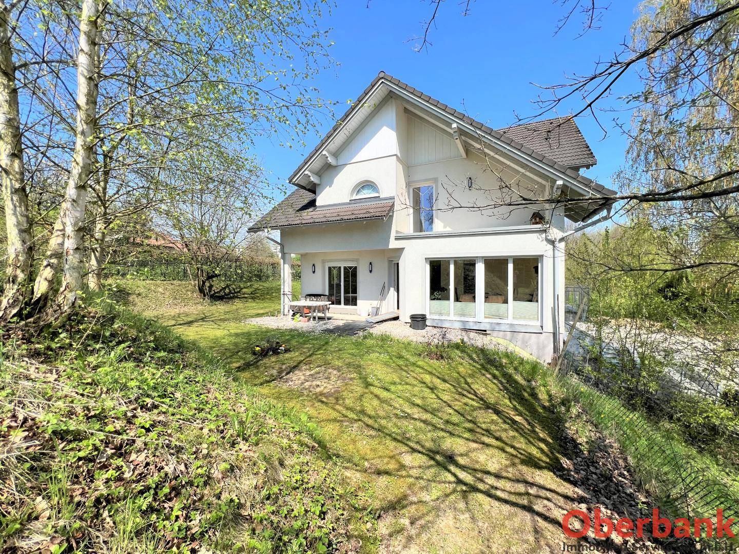 Ansicht des Einfamilienhauses von der Seite mit Terrasse und großen Fenstern zum Garten.