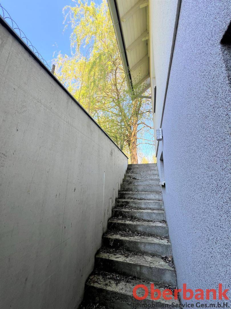 Steile Außentreppe aus Beton zwischen zwei Mauern, die zu einem höher gelegenen Bereich führt.