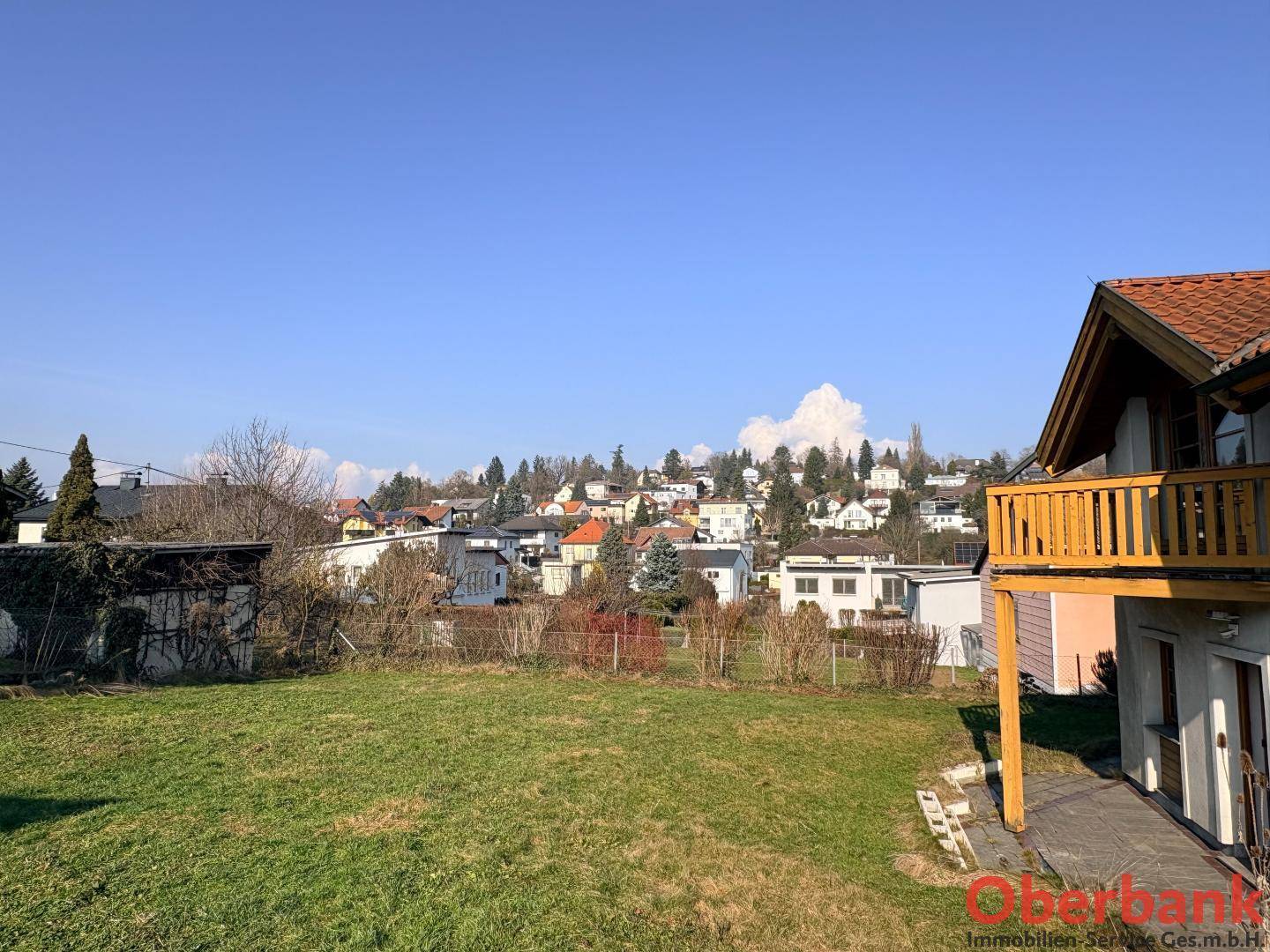 Weitläufiger Gartenbereich mit Blick auf die umliegende Wohnsiedlung und grüne Hügel.