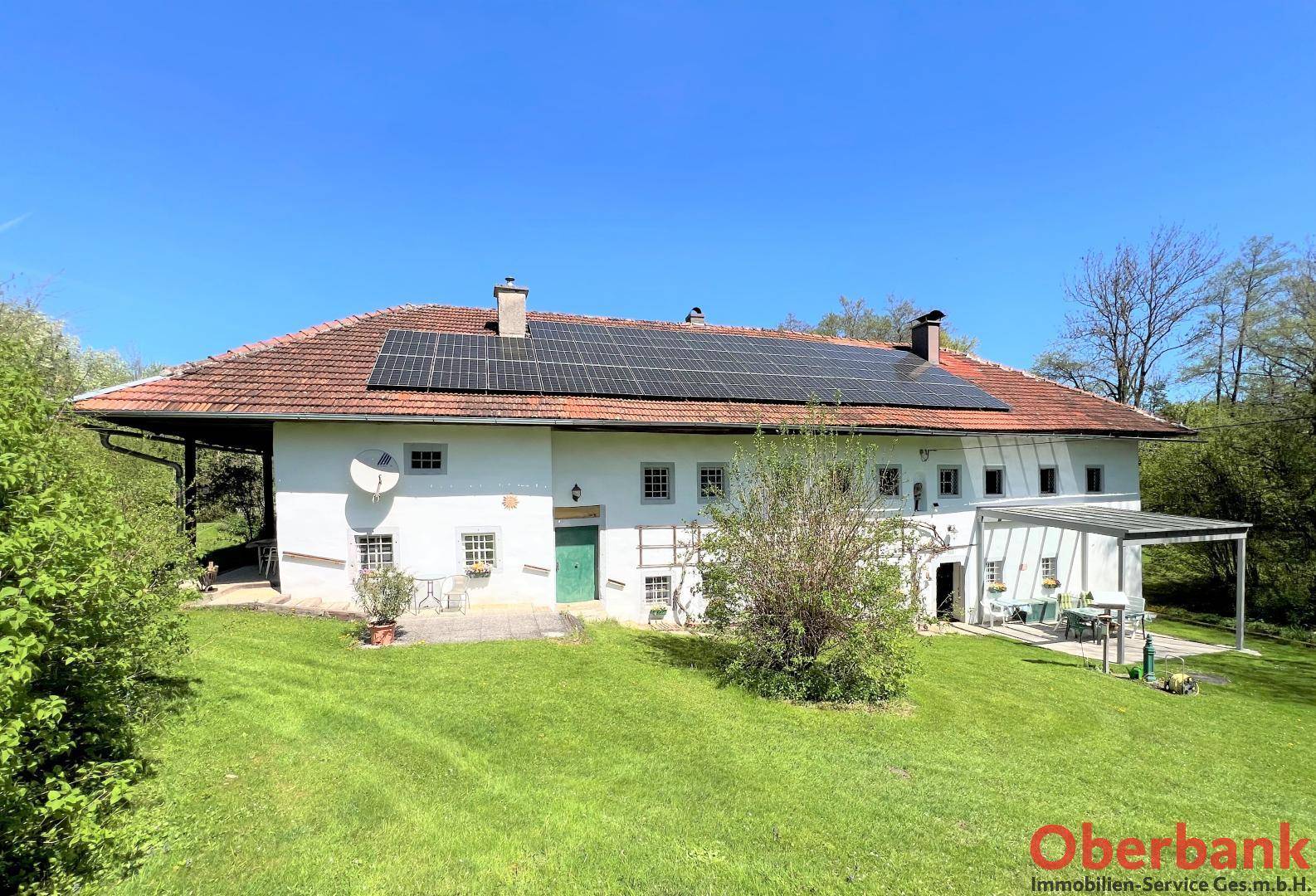 Weitläufiges Bauernhaus mit Photovoltaikanlage auf dem Ziegeldach und einer kleinen überdachten Terrasse.