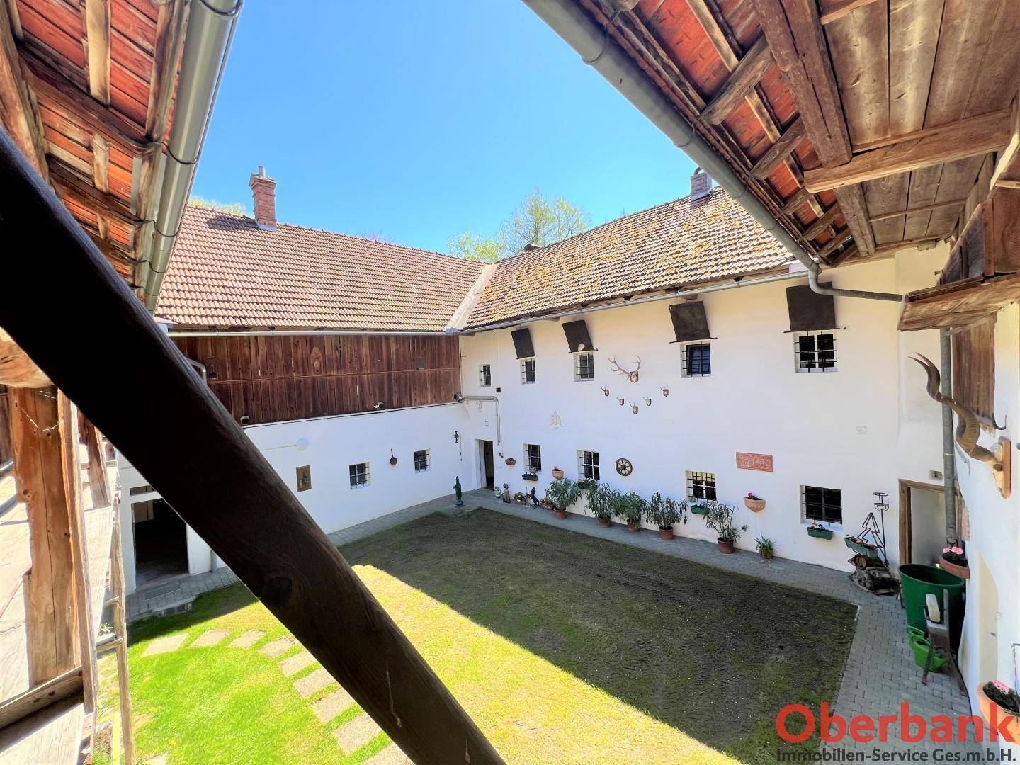 Blick von oben auf den gepflegten Innenhof mit Rasenfläche, umgeben von den Gebäudeteilen des Bauernhauses.