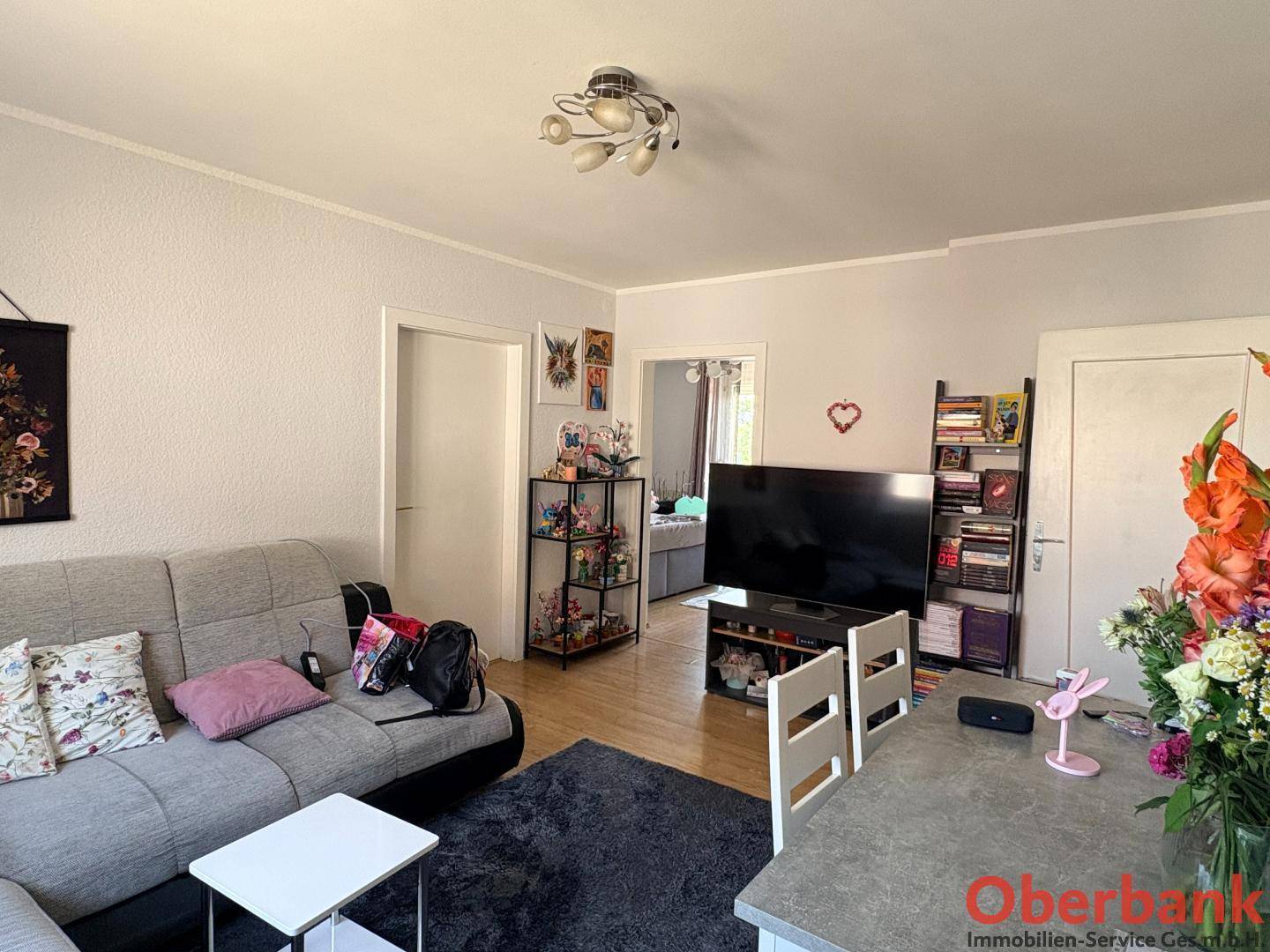 Gemütlicher Wohn-Essbereich mit Sofa, Fernseher und einem Esstisch im Vordergrund.