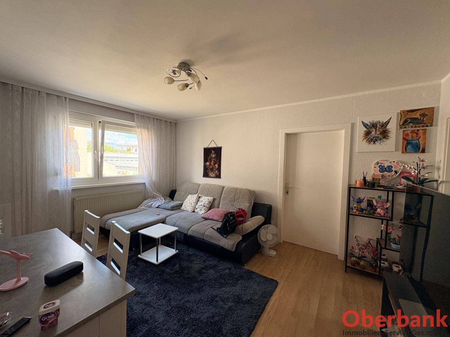 Heller Wohnbereich mit Sofa, Esstisch und einem großen Fenster für viel Tageslicht.