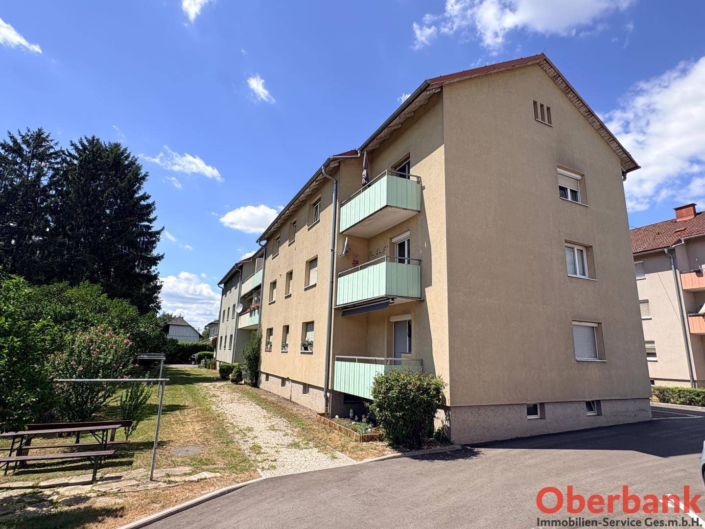 Ansicht des Mehrfamilienhauses von der Seite mit mehreren Balkonen und Grünflächen.