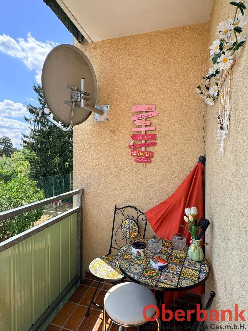 Kleiner Balkon mit Mosaiktisch, Stühlen und einer Satellitenschüssel für Unterhaltung.