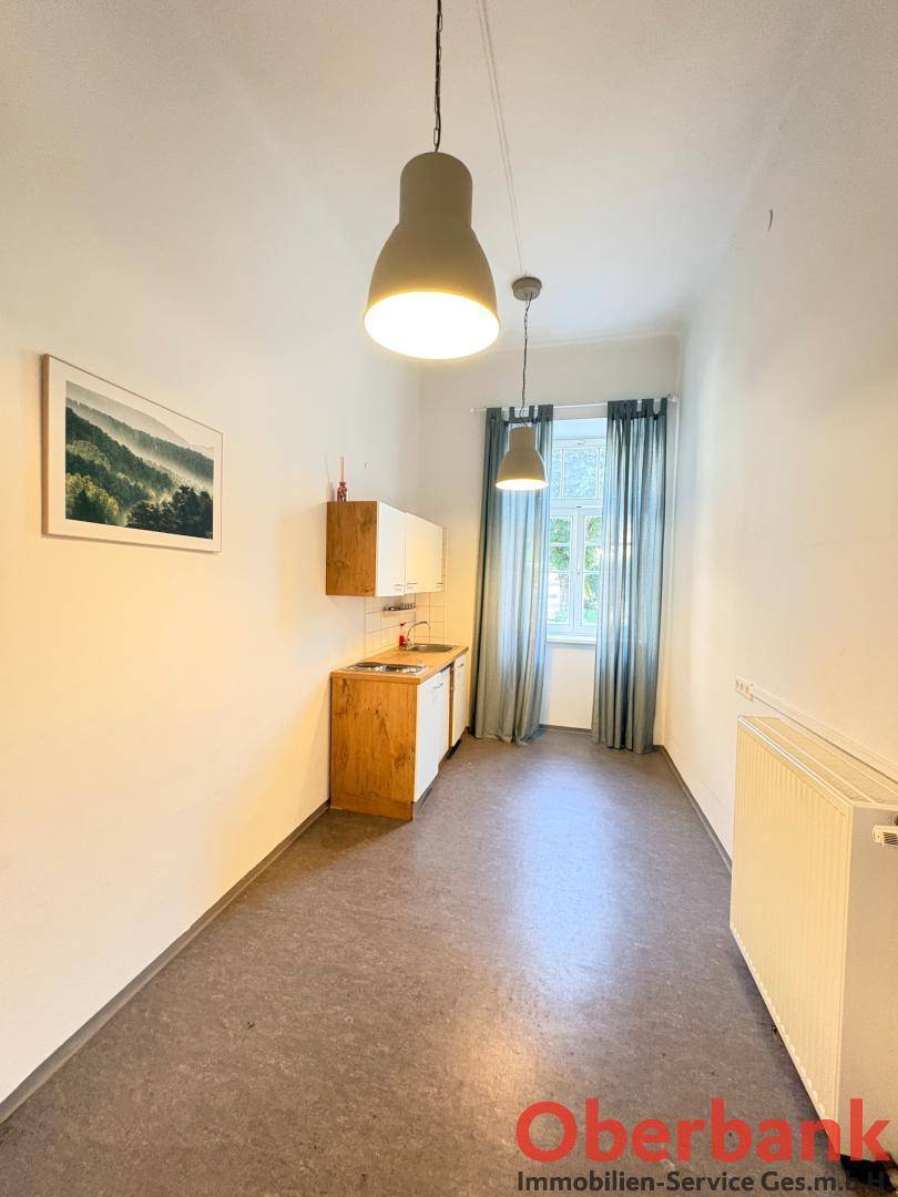 Kleiner Raum mit einfacher Küchenzeile, Fenster und zwei Hängelampen, ideal als Teeküche.