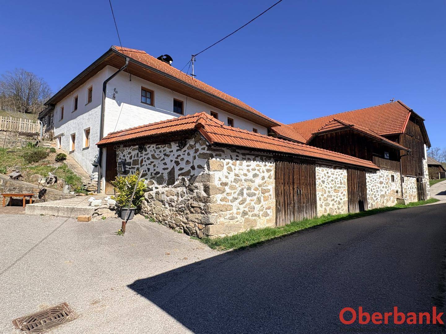 Ländliches Anwesen mit weiß getünchtem Haupthaus und angrenzenden Wirtschaftsgebäuden, eingebettet in die Landschaft.
