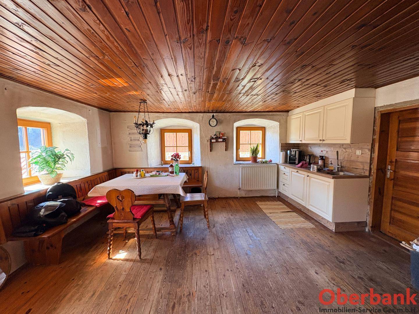 Gemütliche Wohnküche mit Holzboden, Holzdecke und traditionellem Essbereich, hell und einladend.