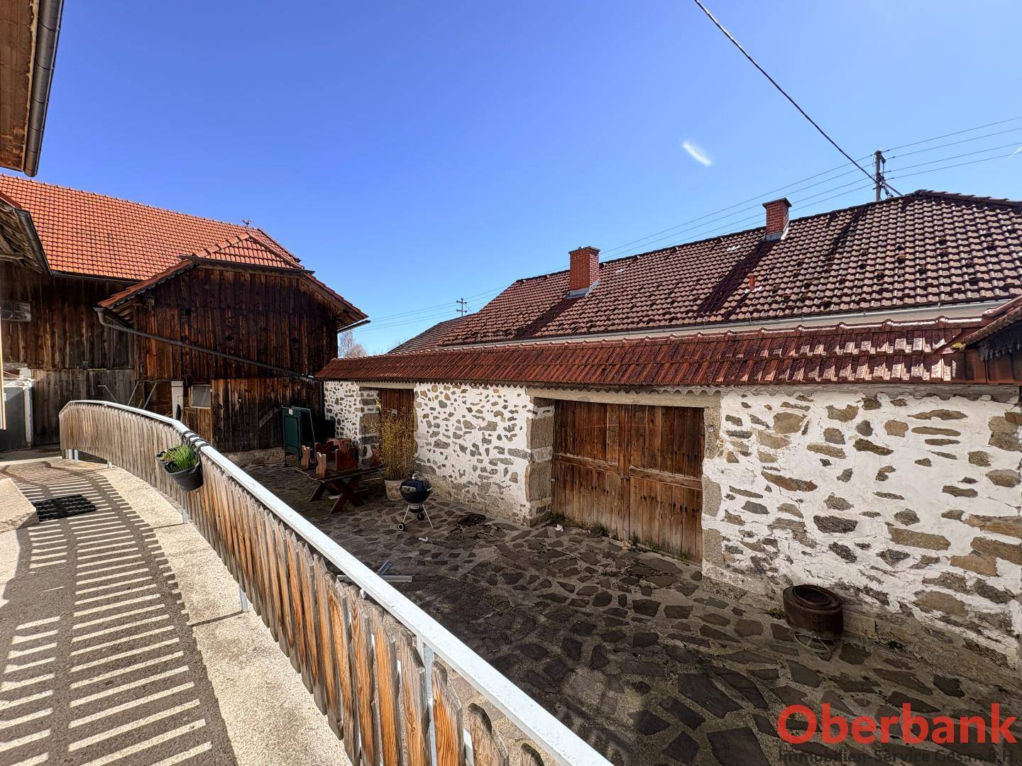 Rustikaler Innenhof zwischen den Gebäuden mit Steinfliesen, Grillbereich und traditionellem Charme.