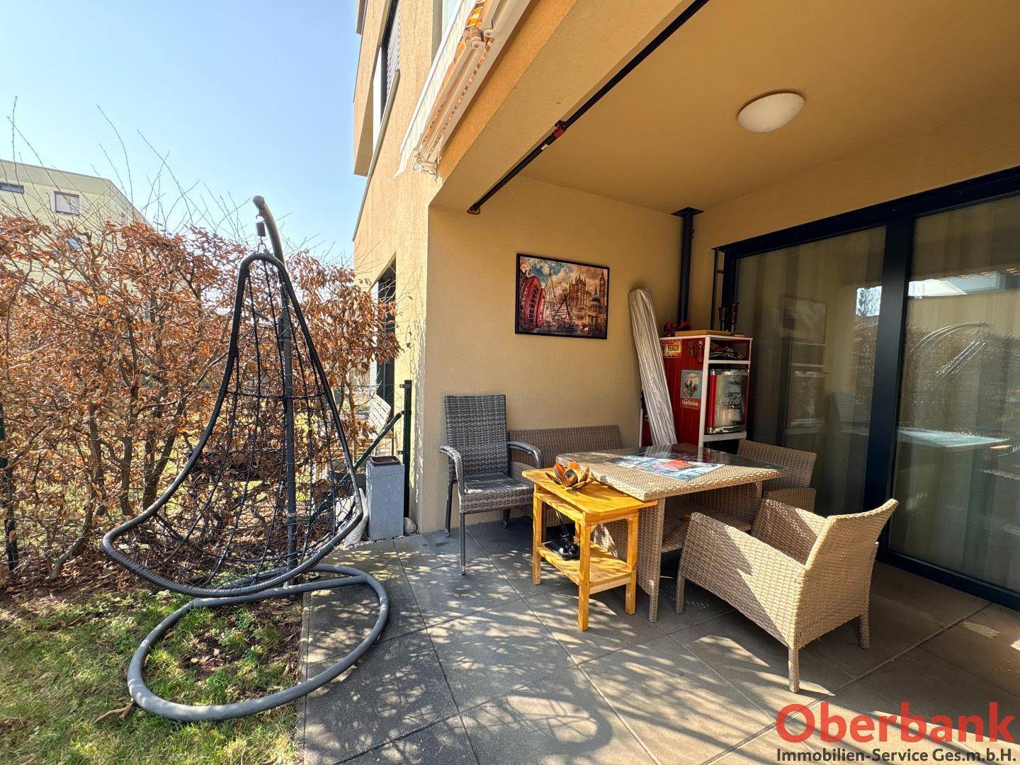 Gemütliche, überdachte Terrasse mit Gartenmöbeln und einem Hängesessel für Entspannung im Freien.