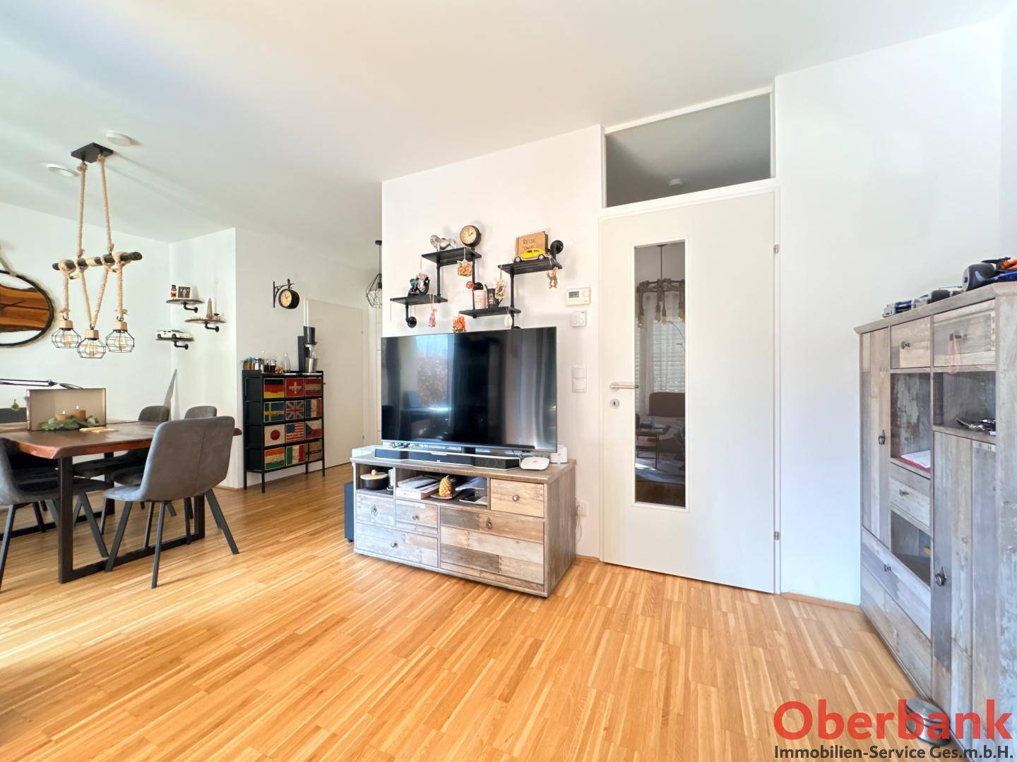 Heller Wohn- und Essbereich mit Holzparkettboden, modernem Esstisch und TV-Möbel.