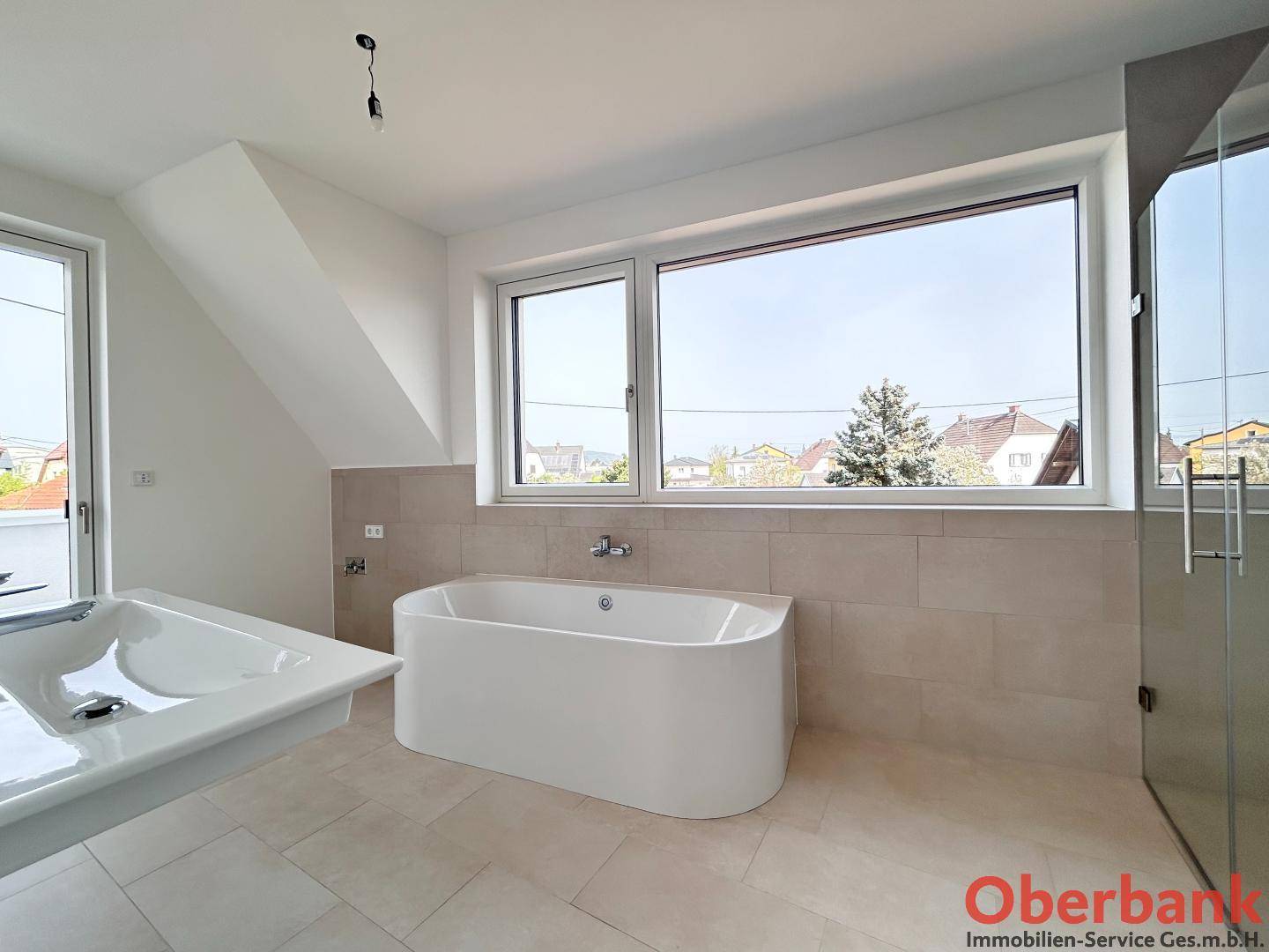 Modernes Badezimmer mit freistehender Badewanne, großem Fenster und Fliesenboden.