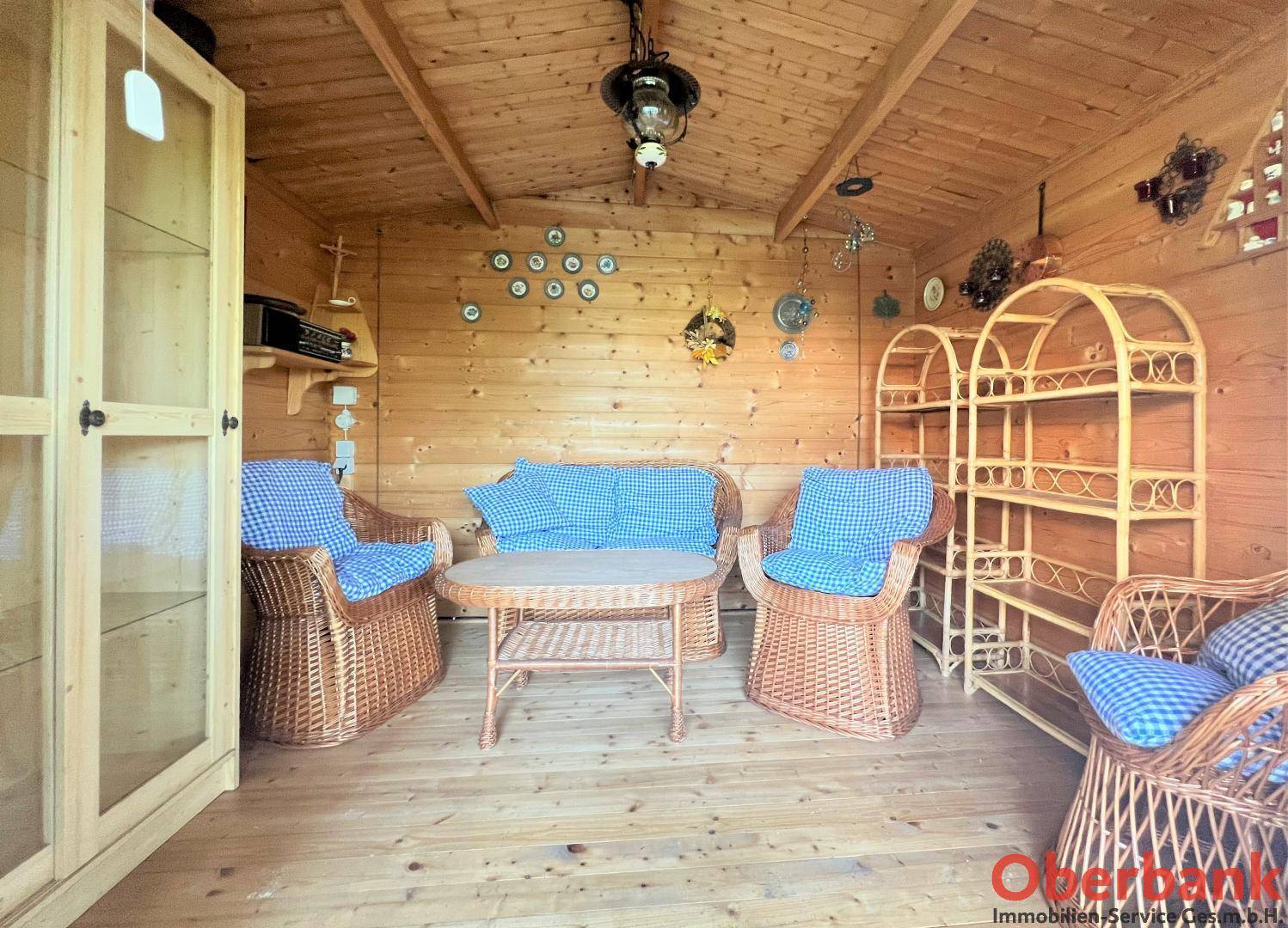 Gemütlicher Innenraum des Gartenhäuschens mit Holzverkleidung und Korbmöbeln, ideal zum Entspannen.