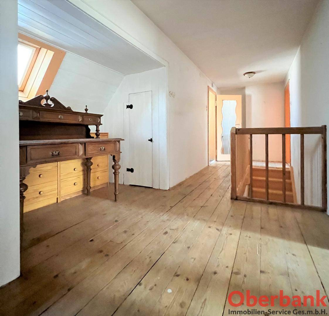 Heller Flurbereich im Dachgeschoss mit Holzfußboden und Dachfenster, bietet Zugang zu weiteren Räumen.