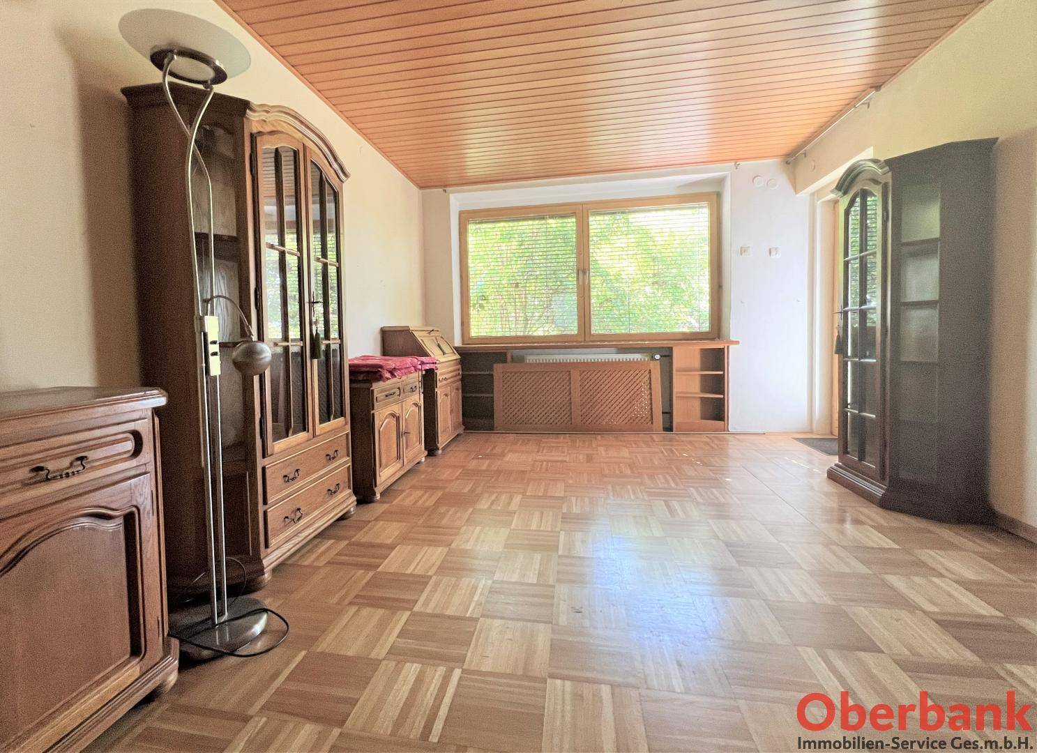 Helles Wohnzimmer mit Holzdecke und Parkettboden, ausgestattet mit traditionellen Holzmöbeln.