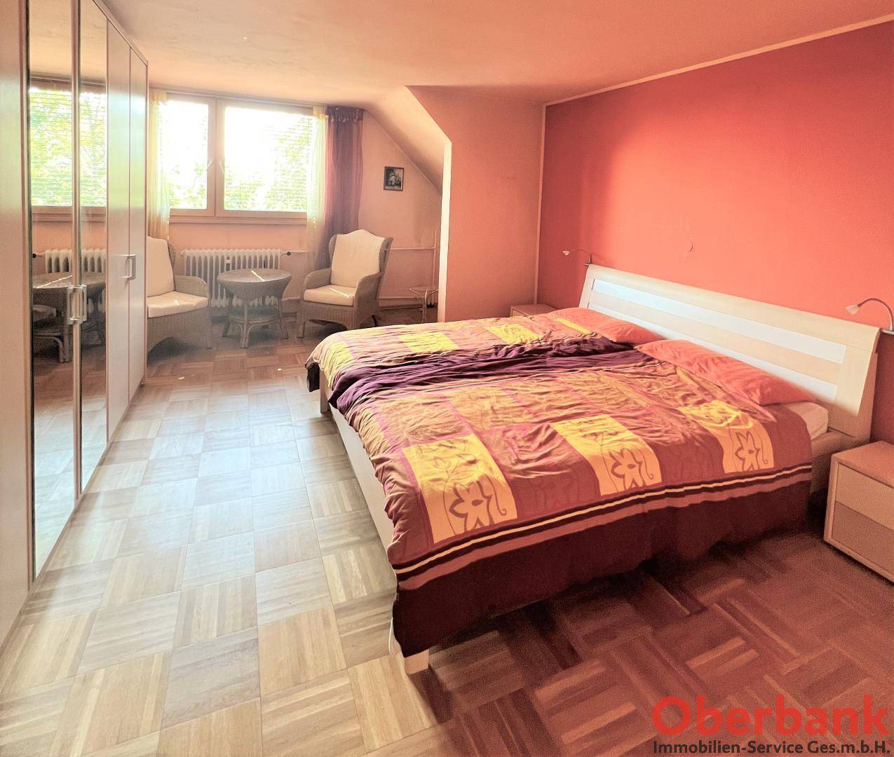 Geräumiges Schlafzimmer mit Parkettboden und großen Fenstern, bietet viel Tageslicht und Stauraum.