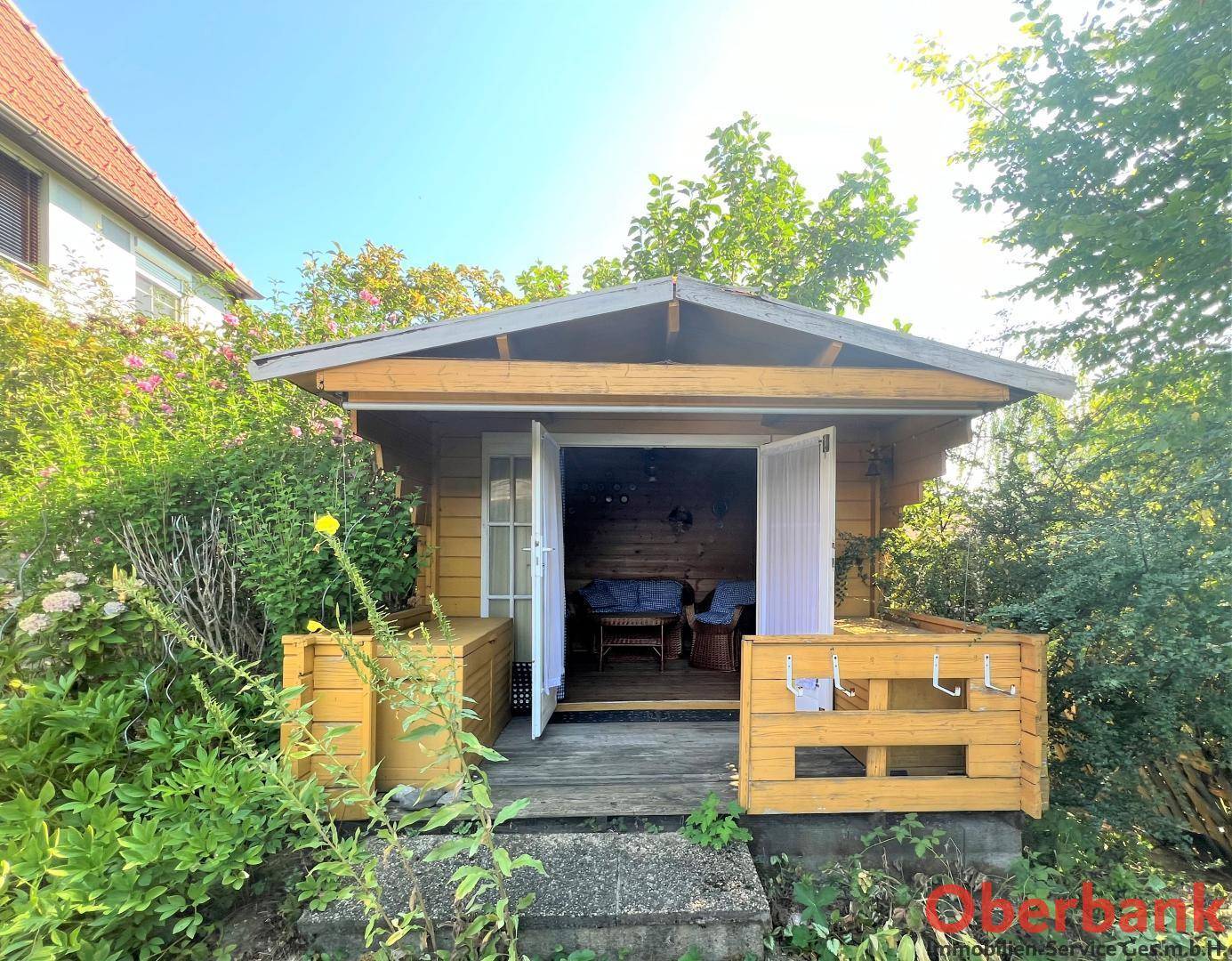 Eingang zum gemütlichen Gartenhäuschen mit kleiner Veranda, ideal als Rückzugsort im Grünen.