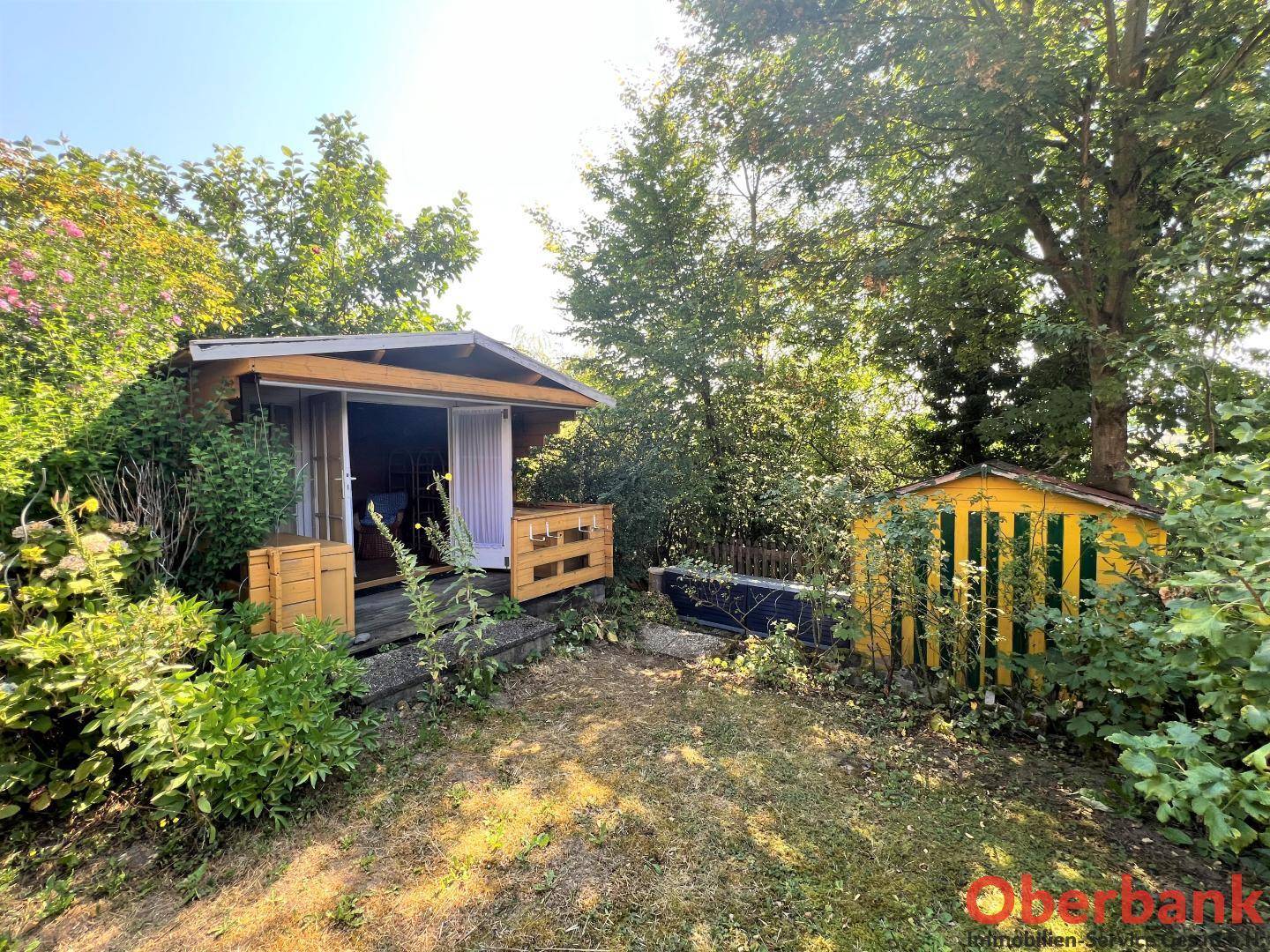 Charmantes Gartenhäuschen aus Holz, umgeben von üppigem Grün, bietet zusätzlichen Stauraum.