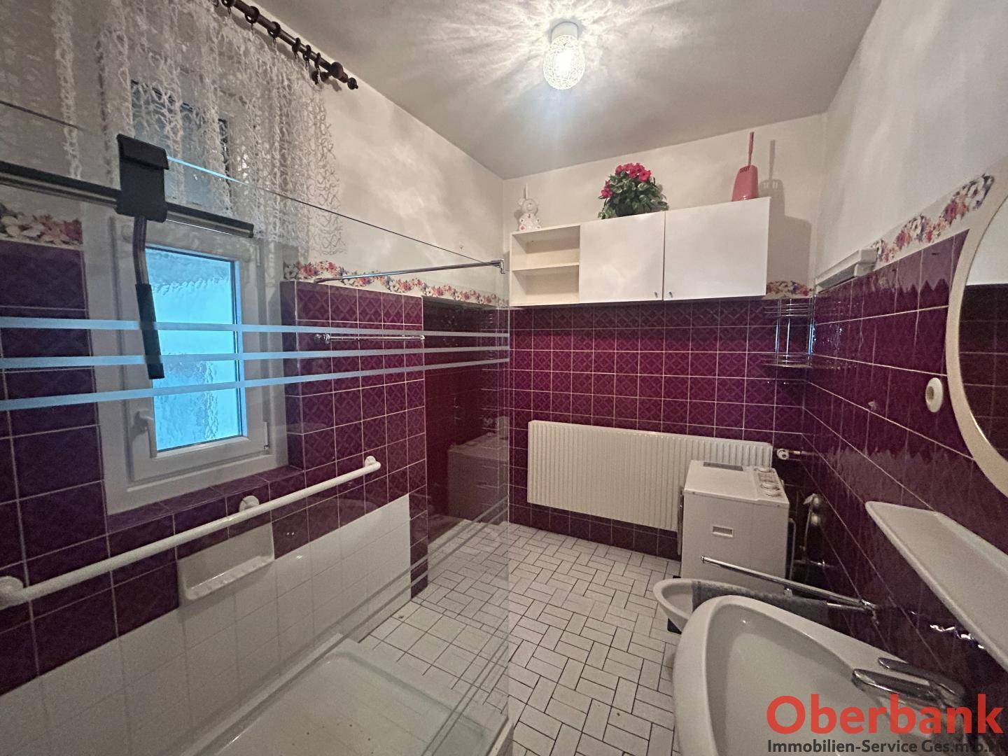 Badezimmer mit lila Fliesen, Badewanne, Bidet und Fenster für natürliche Belüftung.