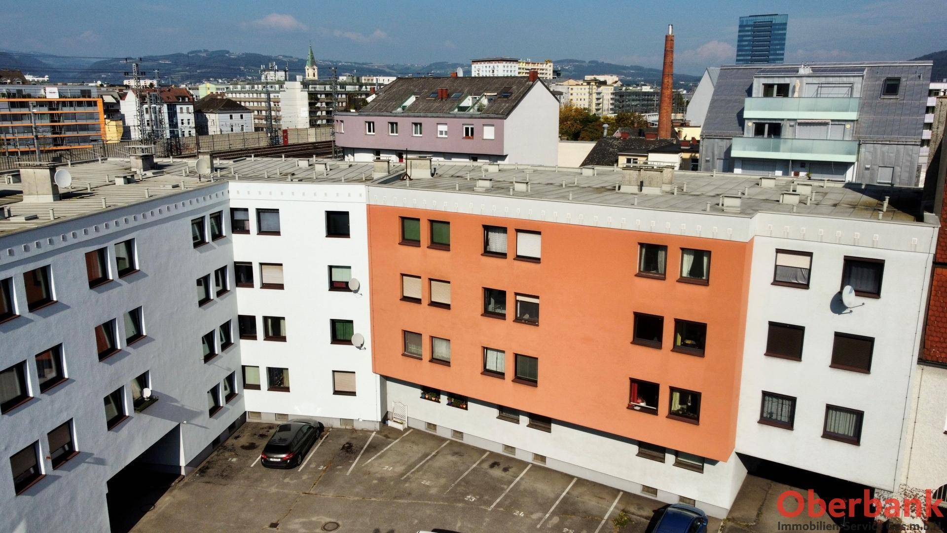 Luftaufnahme eines Wohngebäudes mit Innenhof und umliegender Stadtlandschaft.