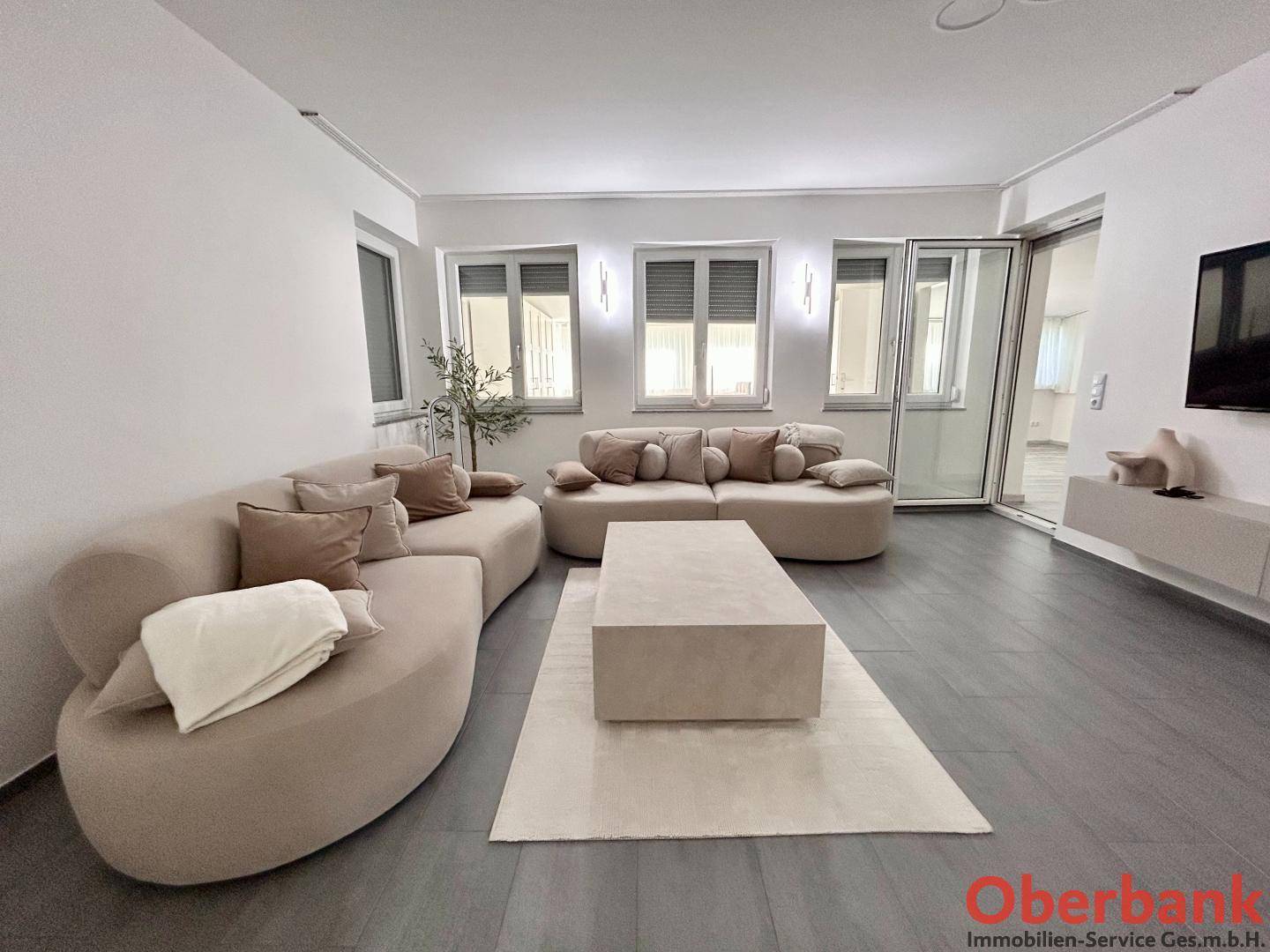 Helles Wohnzimmer mit Zugang zu einem Außenbereich, ausgestattet mit bequemen Sofas.