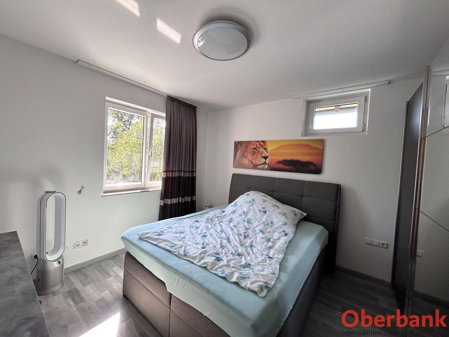 Helles Schlafzimmer mit Doppelbett und Fenster, ausgestattet mit einem Ventilator.