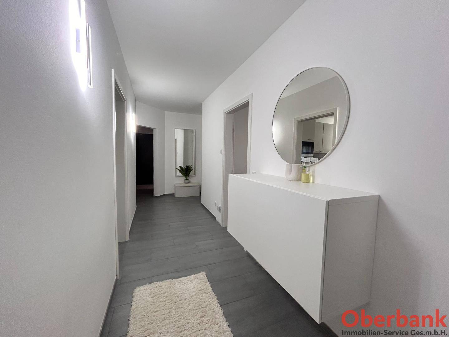 Heller Flur mit modernem Spiegel und schwebendem Sideboard, einladend gestaltet.