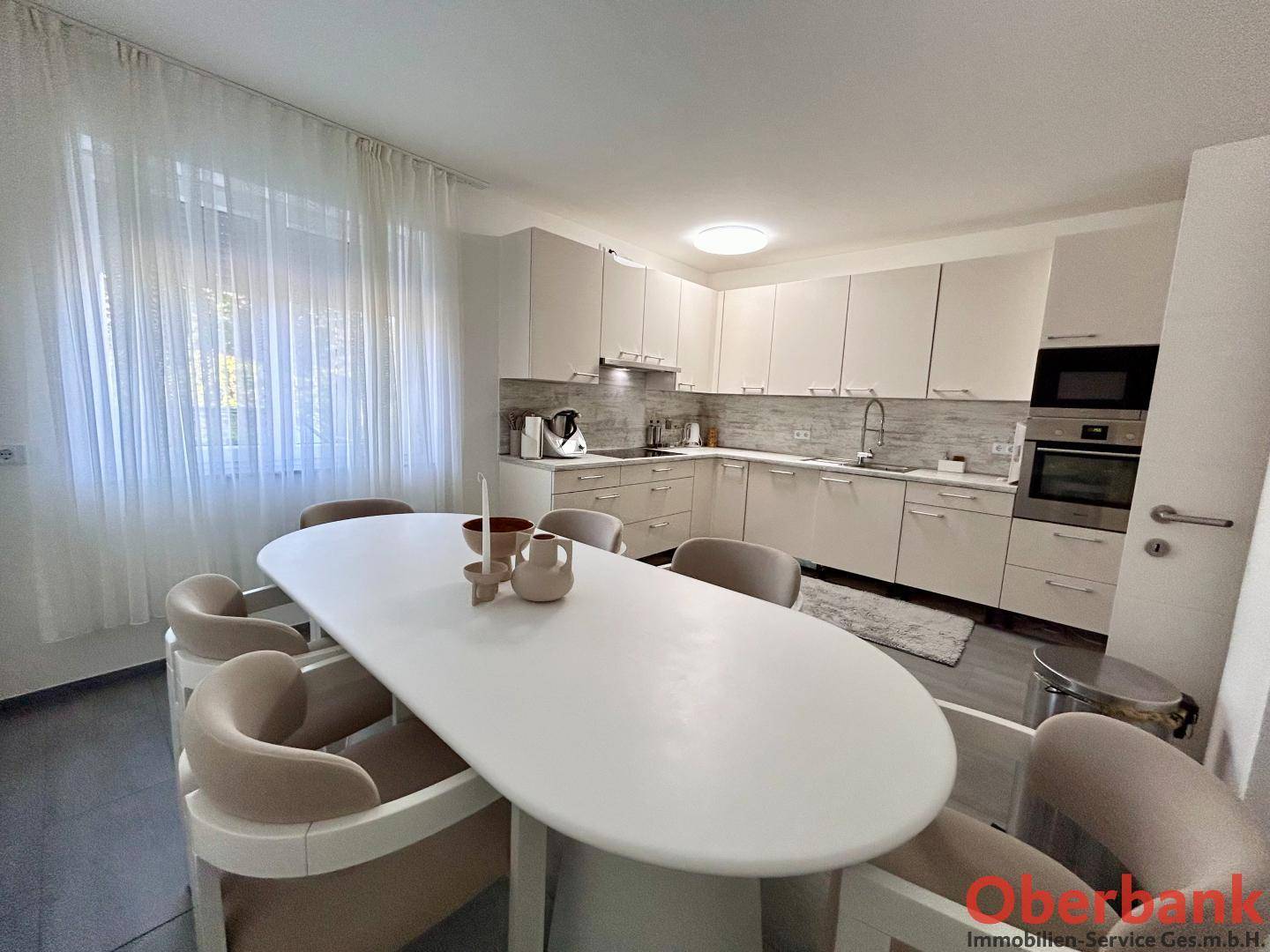 Moderne Einbauküche in hellem Design mit Essbereich und großem Fenster.