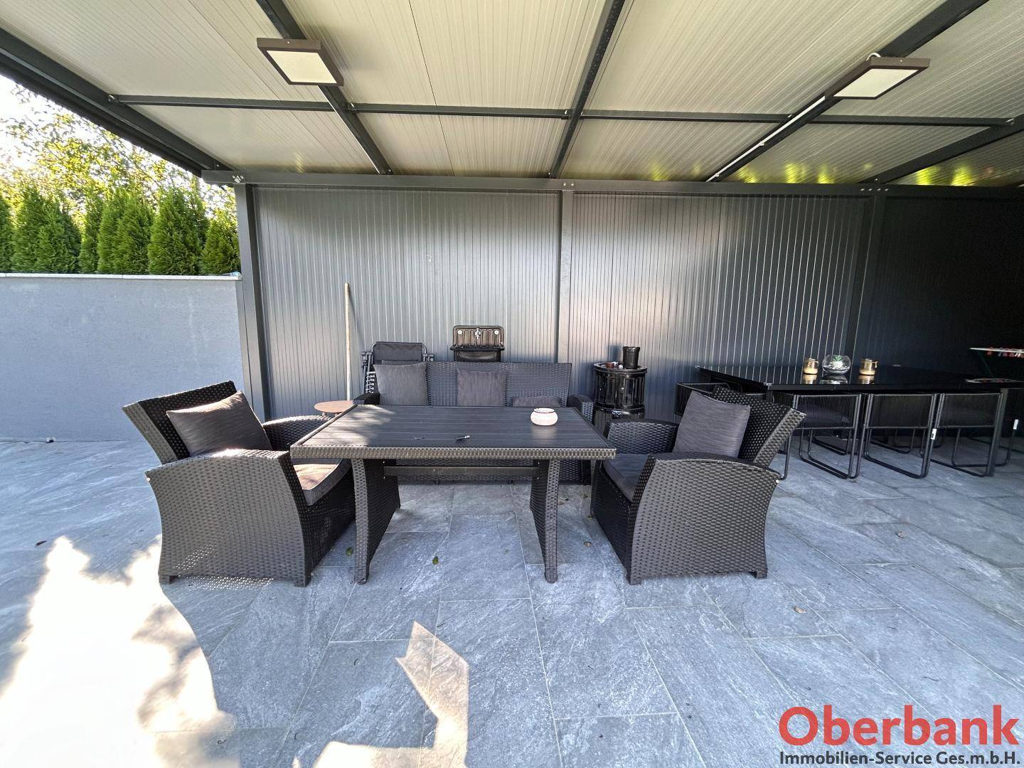Überdachte Terrasse mit bequemen Lounge-Möbeln und Esstisch für gesellige Stunden im Freien.