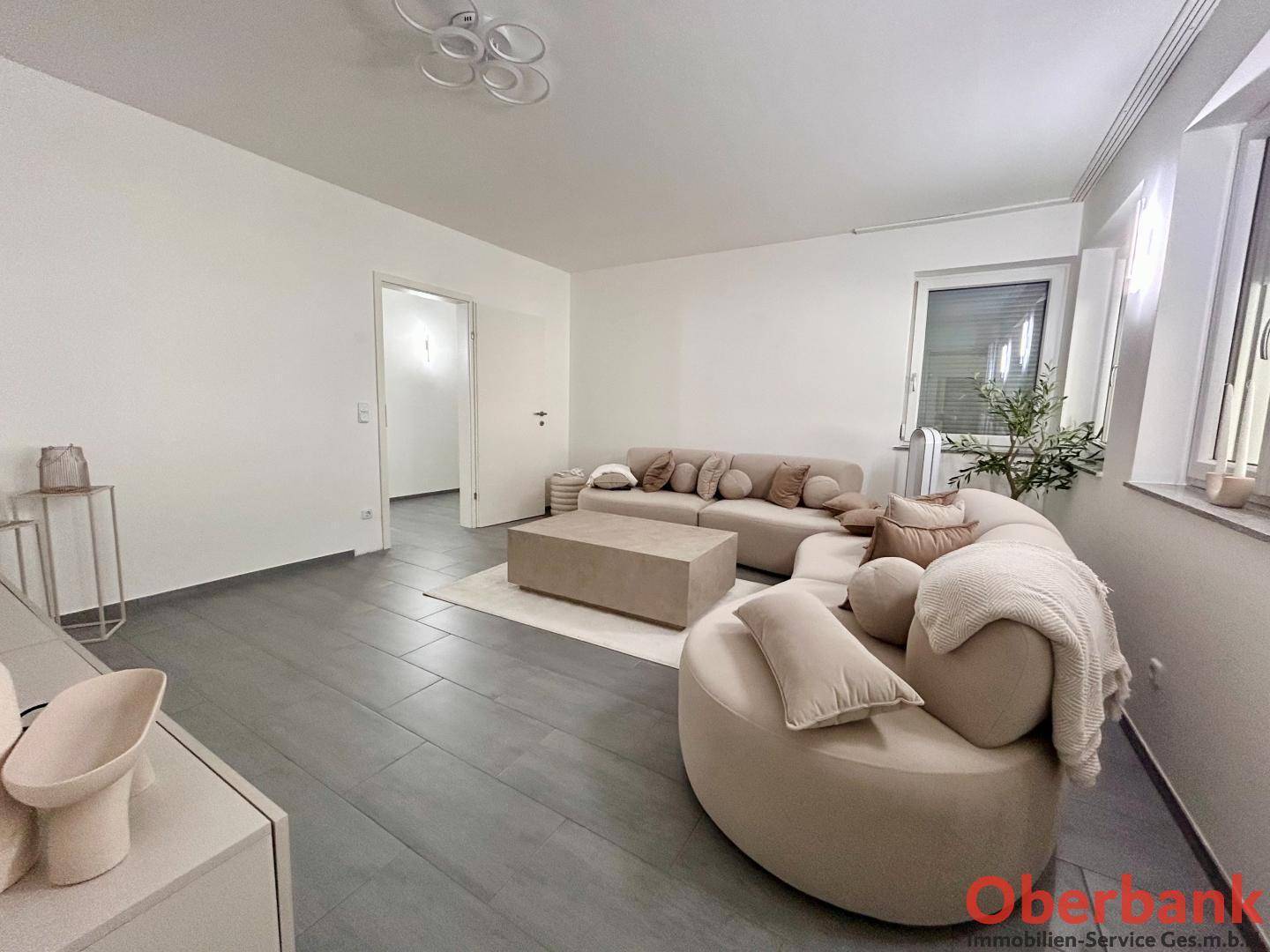 Gemütliches Wohnzimmer mit beigefarbenen Sofas und modernem Couchtisch, hell und einladend.