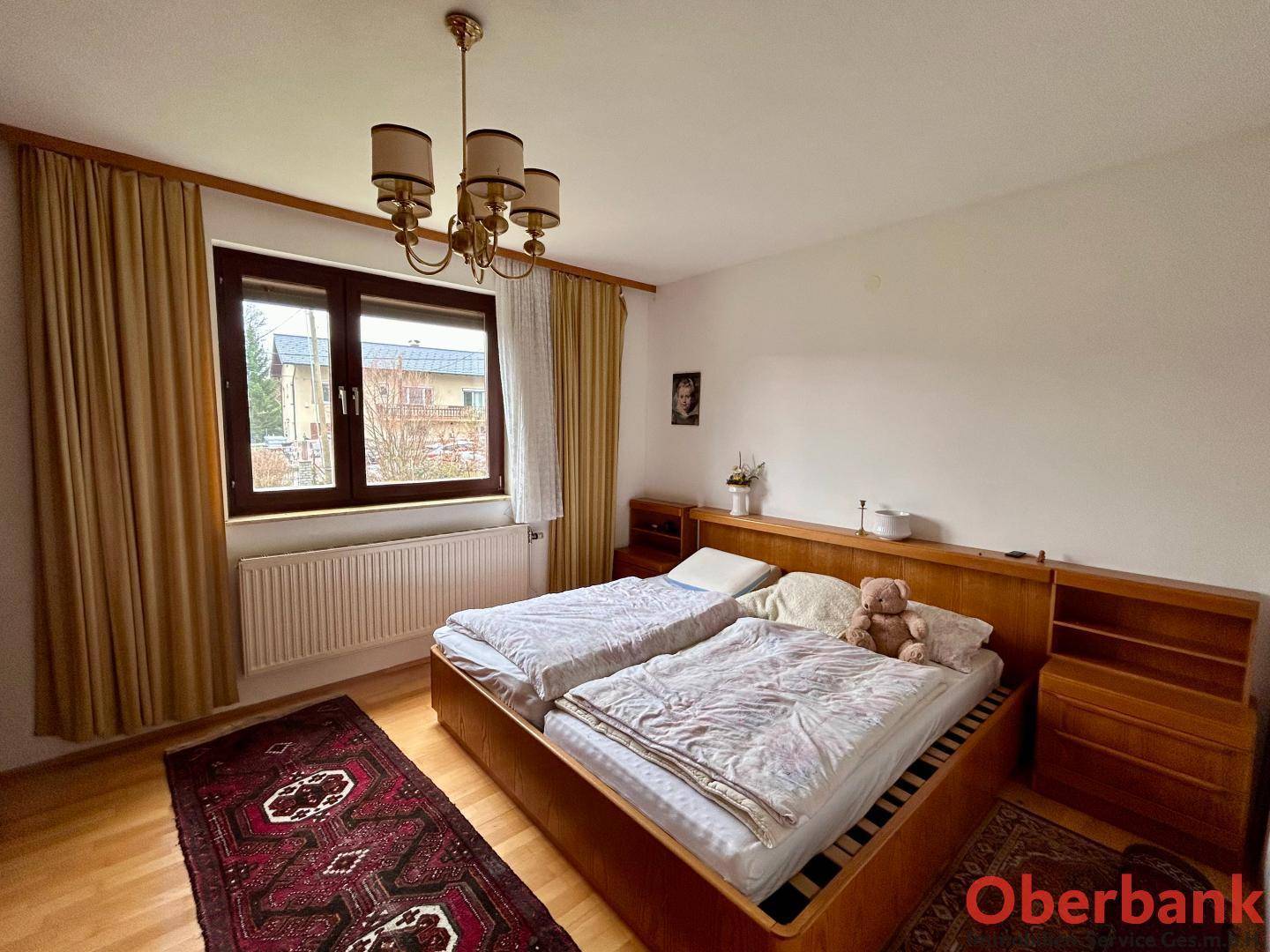 Schlafzimmer mit Doppelbett, Holzmöbeln und Blick ins Grüne durch das Fenster.