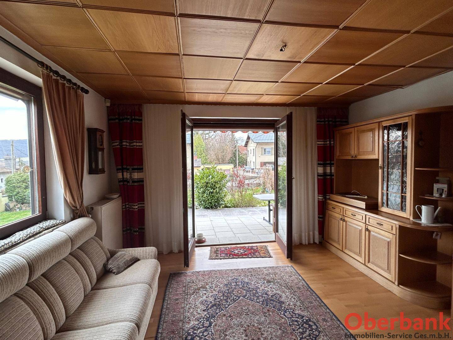 Helles Wohnzimmer mit Holzboden, Holzdecke und direktem Zugang zur Außenterrasse.