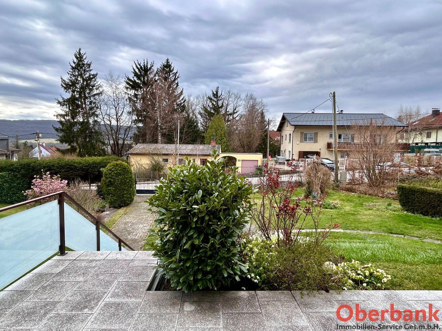 Blick von der Terrasse auf den Garten und die umliegende Landschaft mit Bergen im Hintergrund.