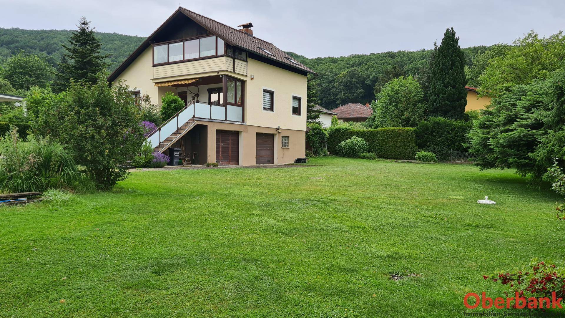 Großer, gepflegter Rasenbereich vor dem Haus mit Blick auf die umliegende Natur.
