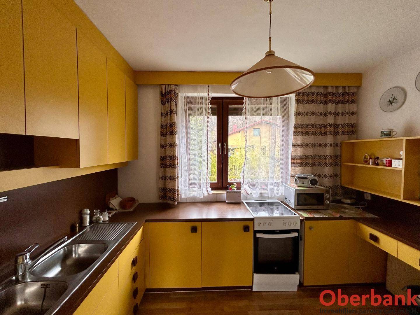 Funktionale Küche im Retro-Stil mit gelben Schränken, Herd und Fensterblick.