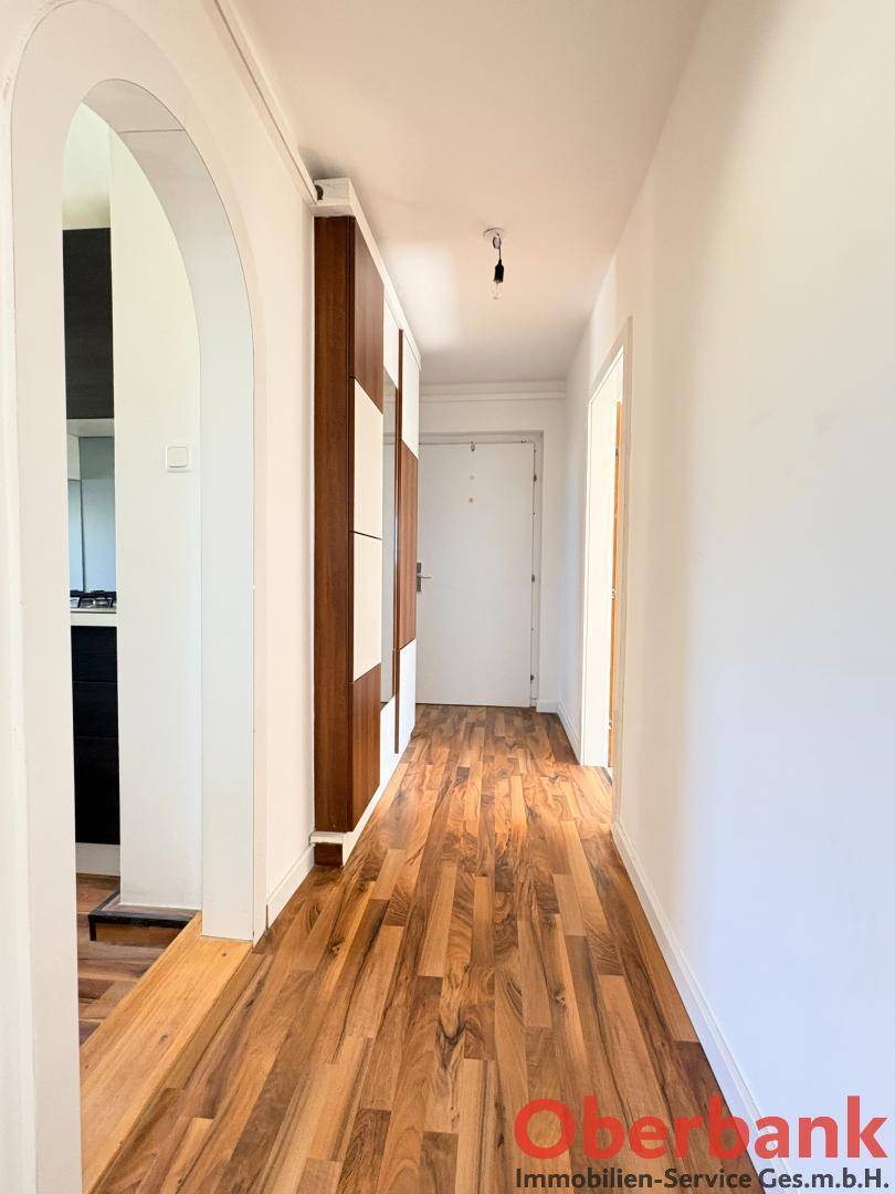 Heller Flur mit Holzboden, weiß gestrichenen Wänden und praktischen Einbauschränken.