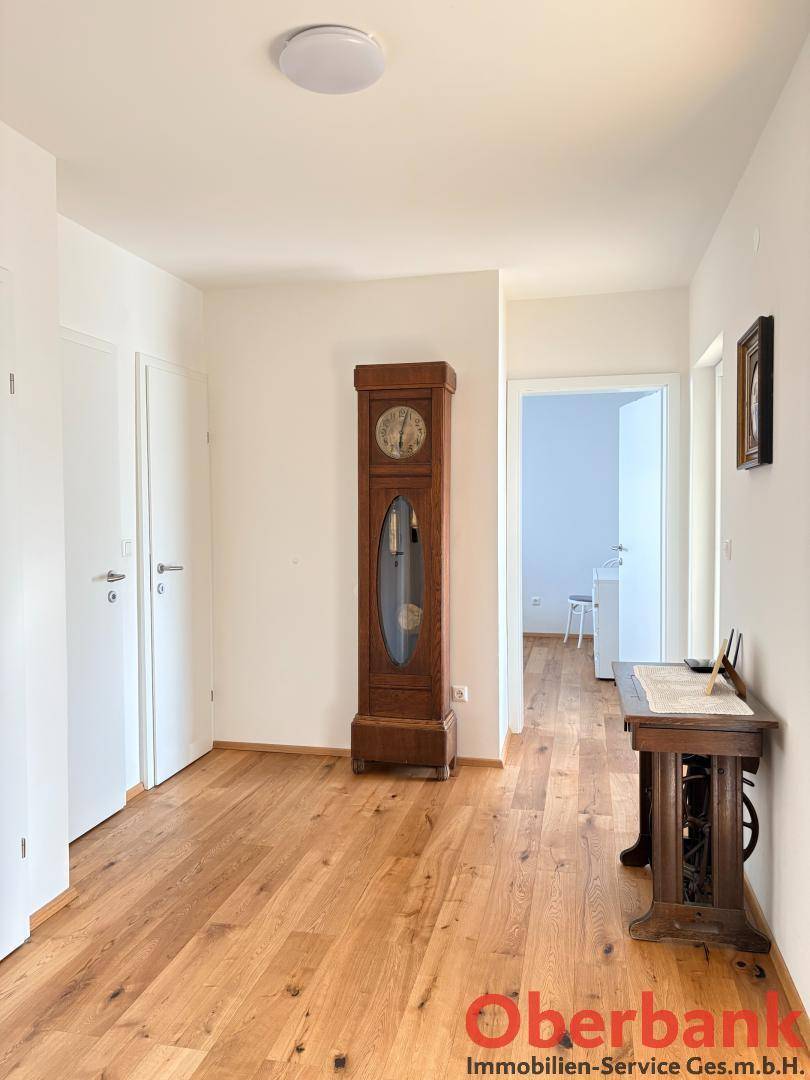 Geräumiger Flur mit Holzboden, einer Standuhr und weißen Türen, die zu weiteren Räumen führen.