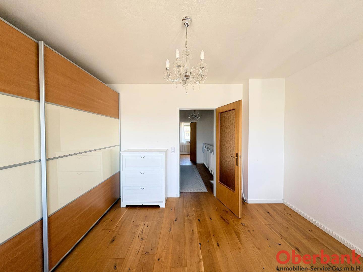 Schlafzimmer mit großem Einbauschrank und Zugang zu einem hellen Flur.
