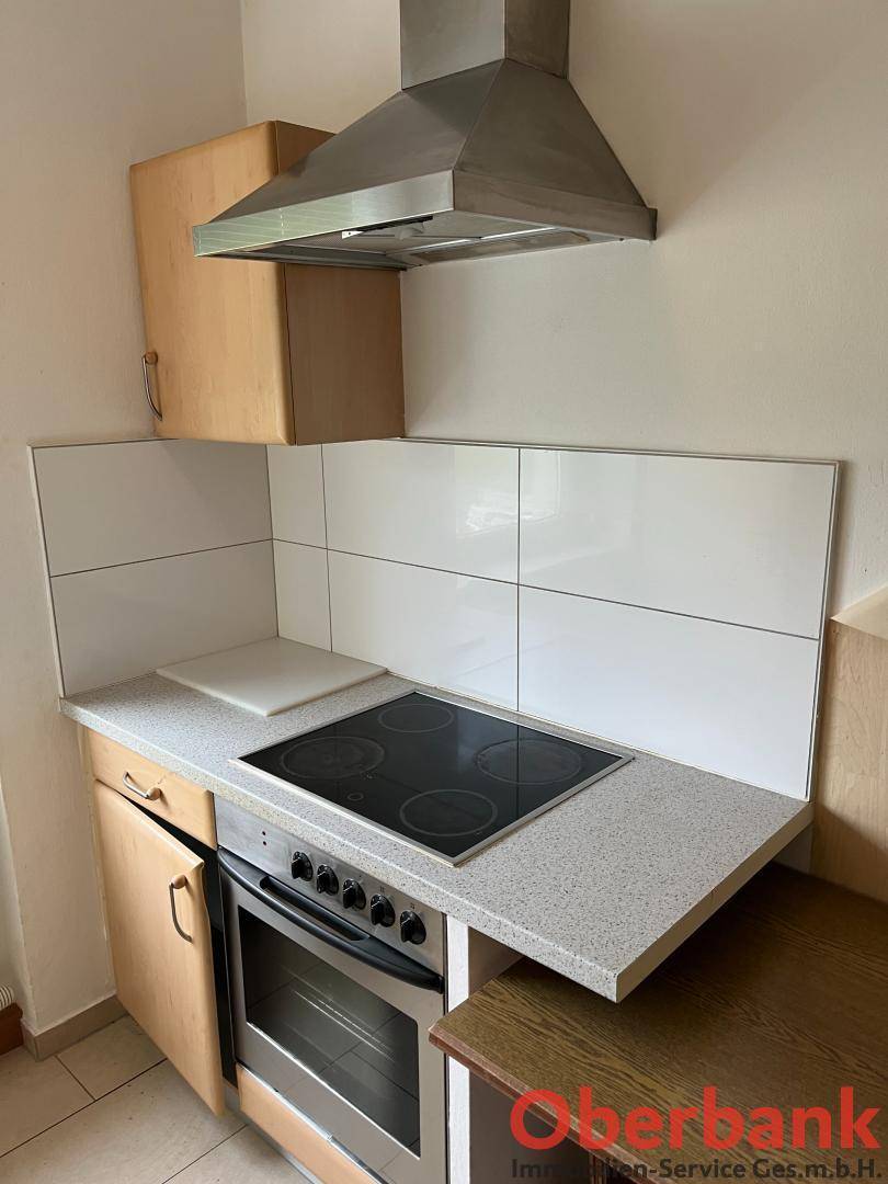Küchenzeile mit Elektroherd, Backofen und Dunstabzugshaube.