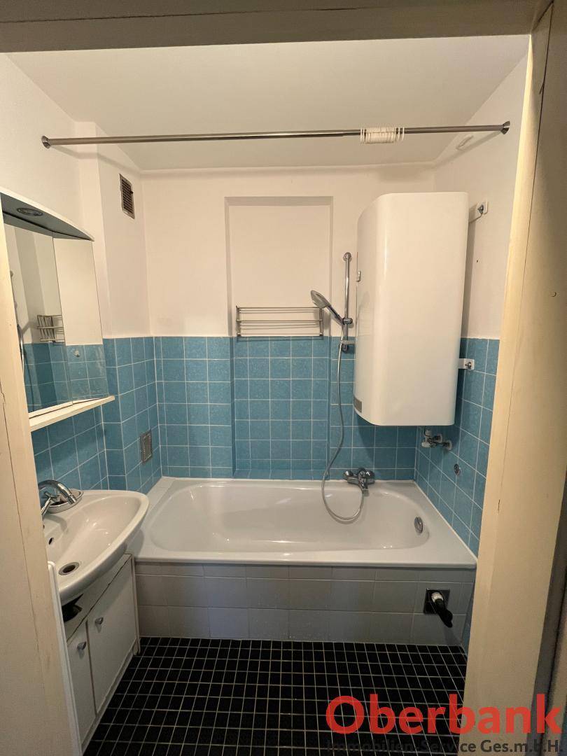 Badezimmer mit Badewanne, Waschbecken und blauen Wandfliesen.