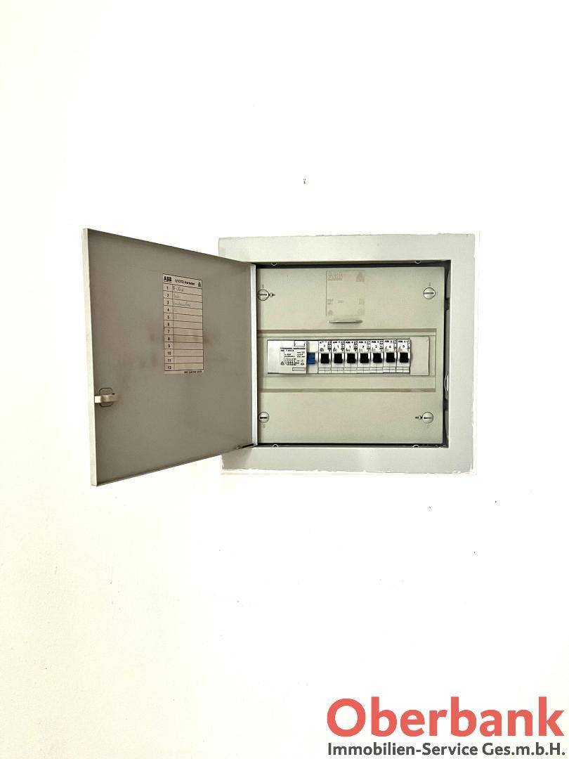 Elektrischer Sicherungskasten an der Wand, offen für Wartungsarbeiten und Inspektionen.
