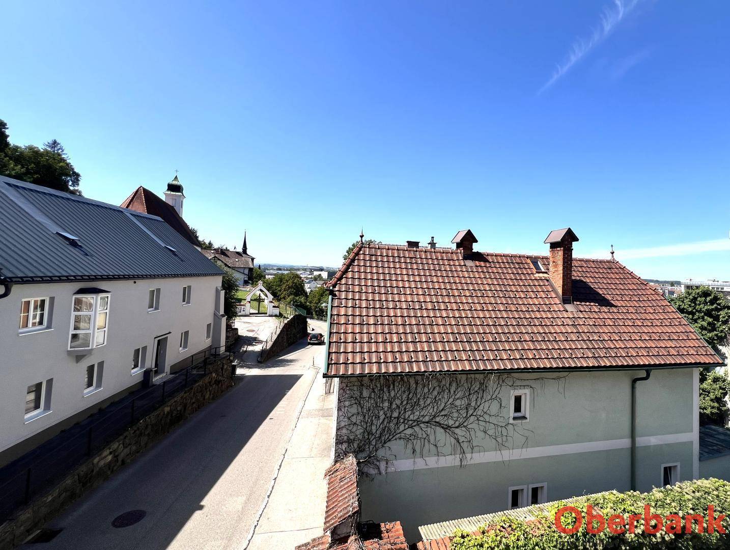 Panoramablick über die Dächer der Stadt mit Kirche und weiter Landschaft im Hintergrund.