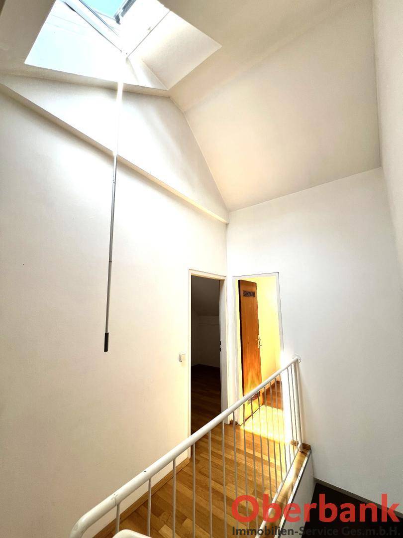 Treppenhaus mit viel Tageslicht durch ein großes Dachfenster, das den Bereich erhellt.