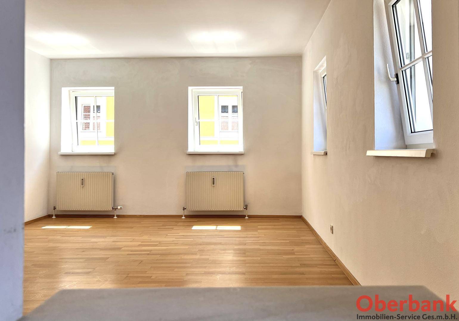 Geräumiger Wohnraum mit Parkettboden und hellen Wänden, ideal für individuelle Gestaltung.