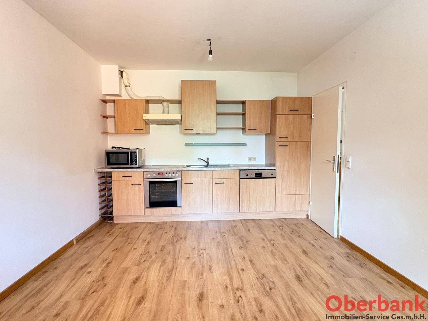 Funktionale Küchenzeile mit Holzschränken, integrierten Geräten und Laminatboden.