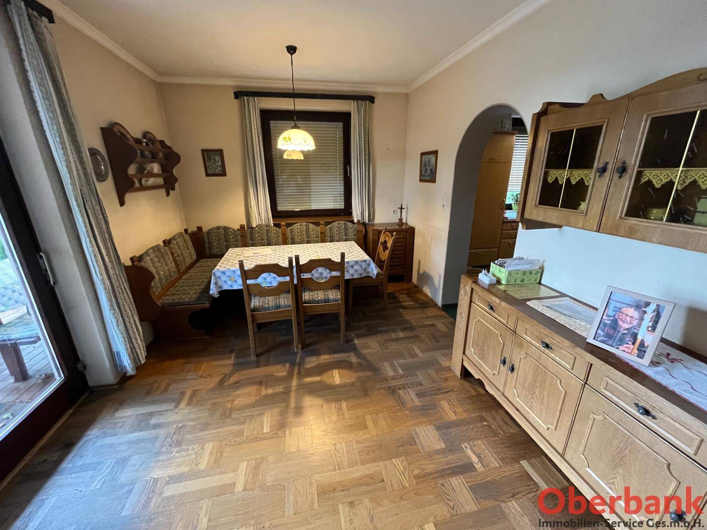 Heller Essbereich mit Holzboden, traditionellen Möbeln und einem Durchgang zur angrenzenden Küche.