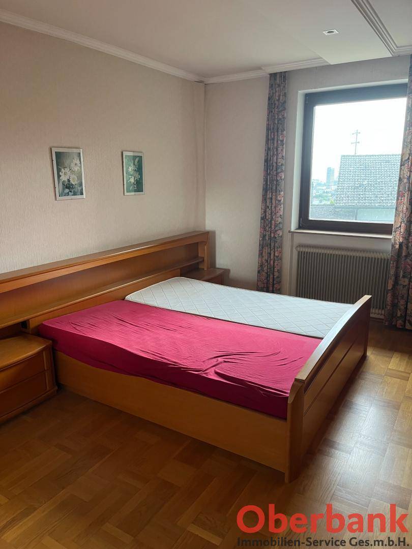 Schlafzimmer mit Doppelbett, Holzmöbeln und einem Fenster, das viel natürliches Licht hereinlässt.