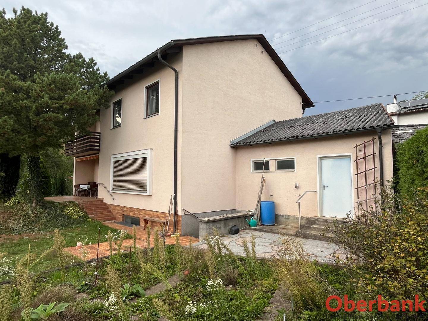 Rückseite des Hauses mit einem gepflegten Gartenbereich und einem kleinen Nebengebäude im Grünen.