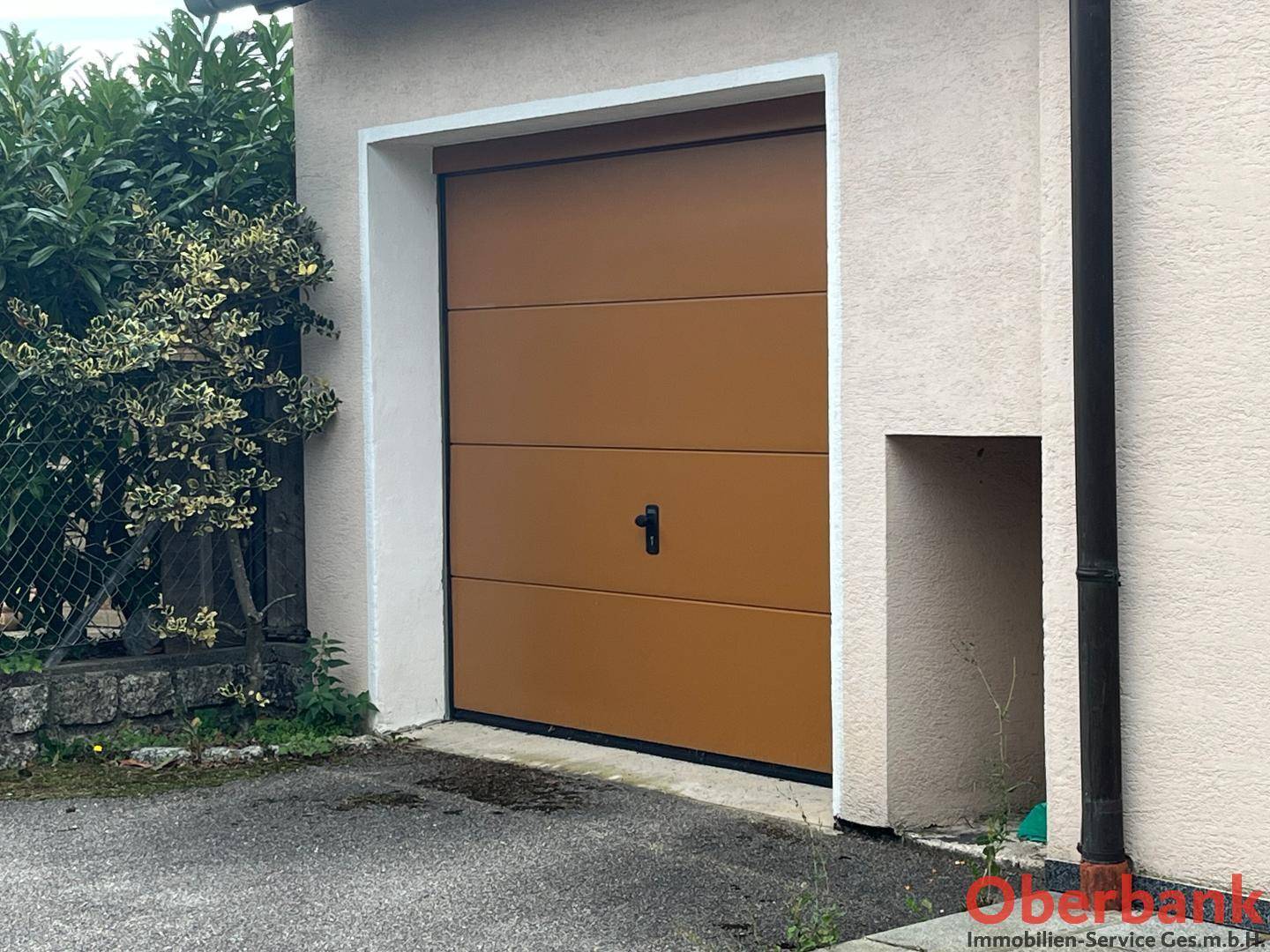 Nahaufnahme des braunen Garagentors mit modernem Design, umgeben von einer hellen Fassade.