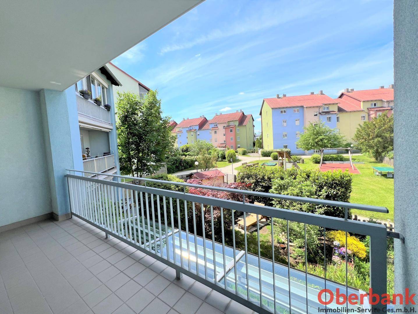 Blick vom Balkon auf den gemeinschaftlichen Spielplatz und die umliegenden Wohngebäude.